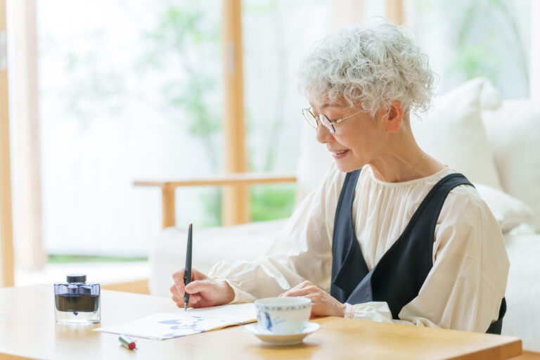 リビングで手紙を書くシニア女性